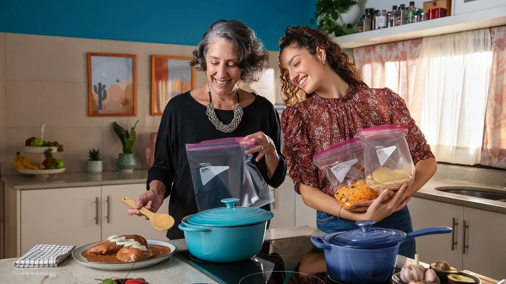 Dos mujeres en una cocina añadiendo comida a bolsas Ziploc®