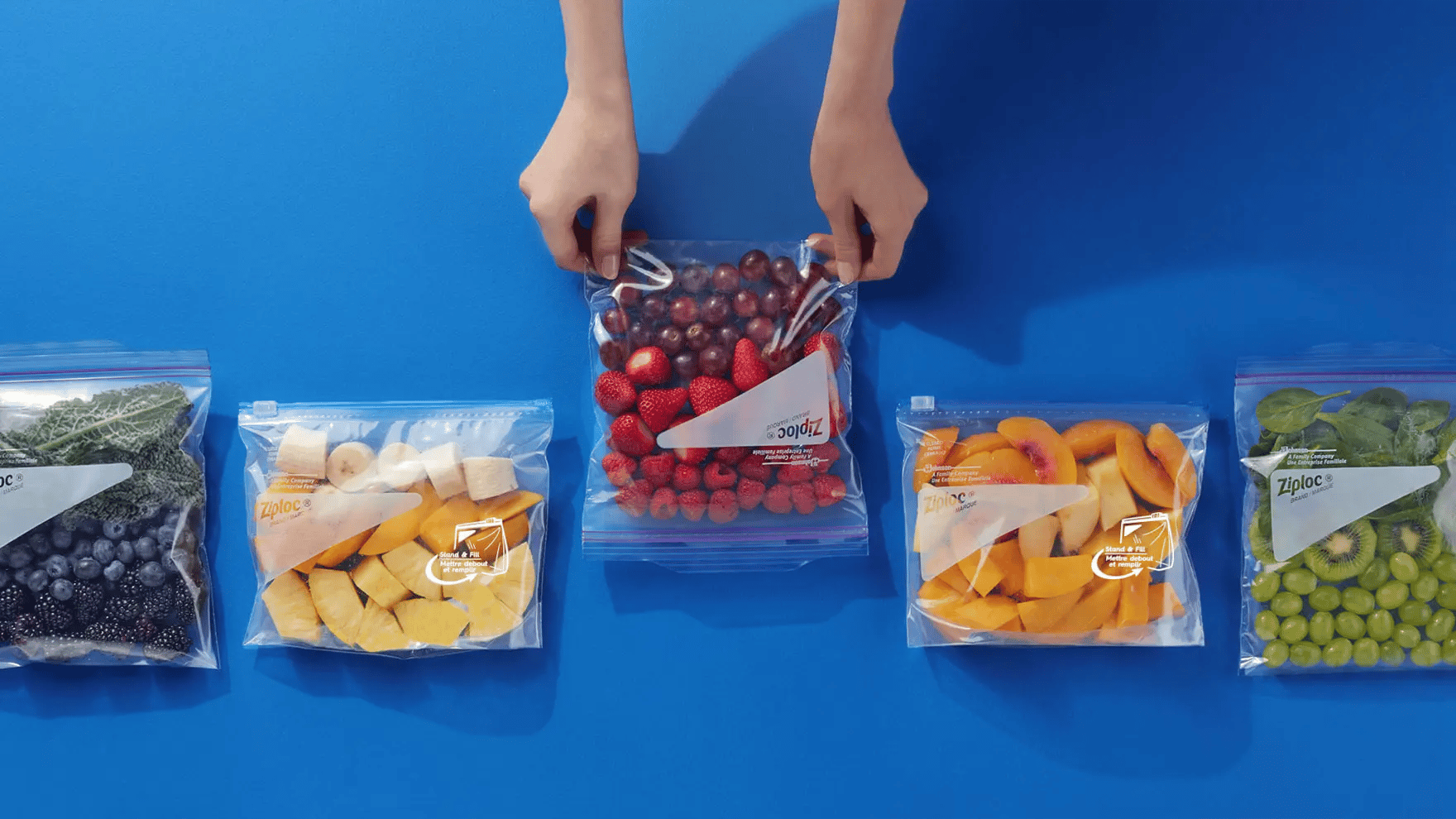 Two hands holding Ziploc bag of fruit
